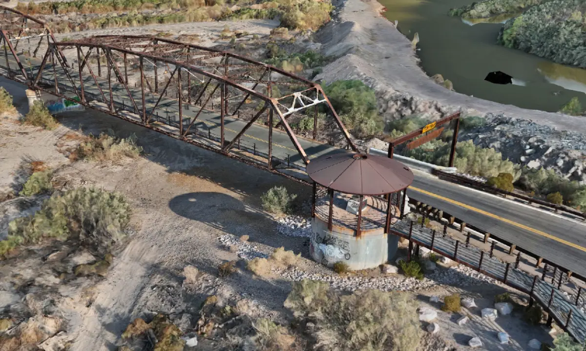 Textured three-dimensional reconstruction of the Gillespie Dam Bridge seen obliquely from above, showing the camelback truss spans, the roadway deck, a concrete pier with its shade structure, and the Gila River channel beyond.